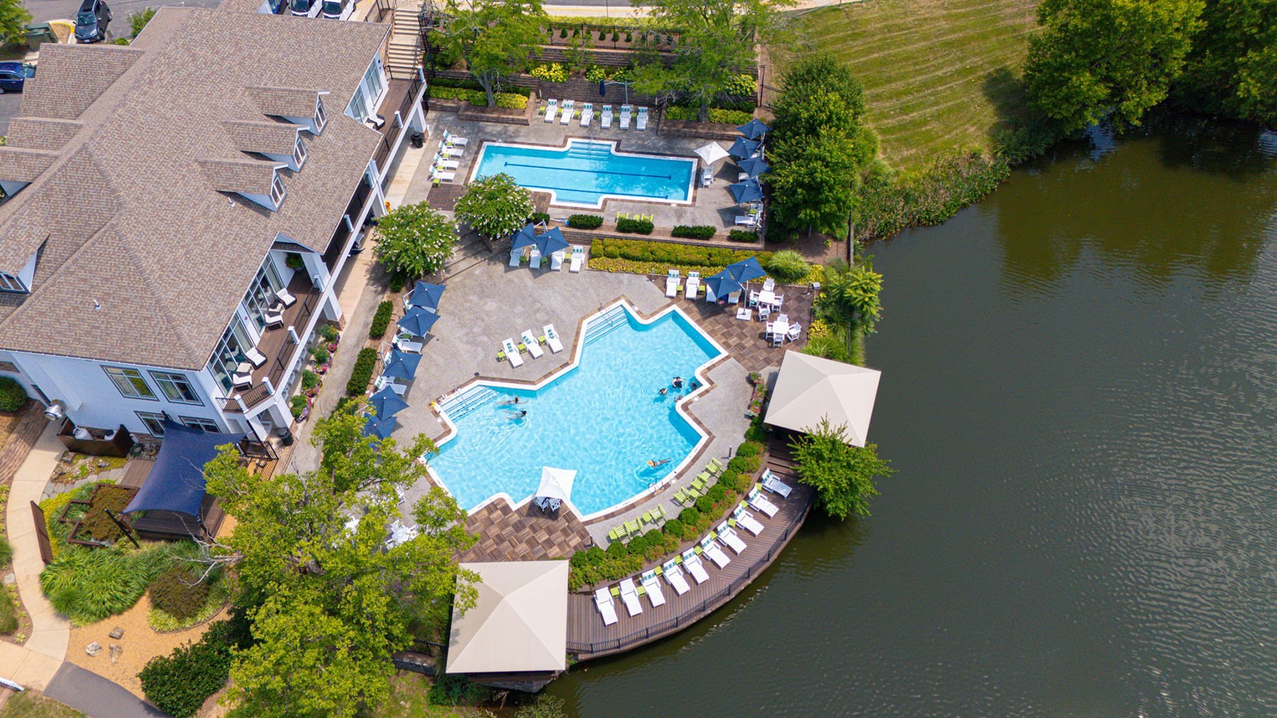 Pool over a body of water surrounded by lush landscaping. 